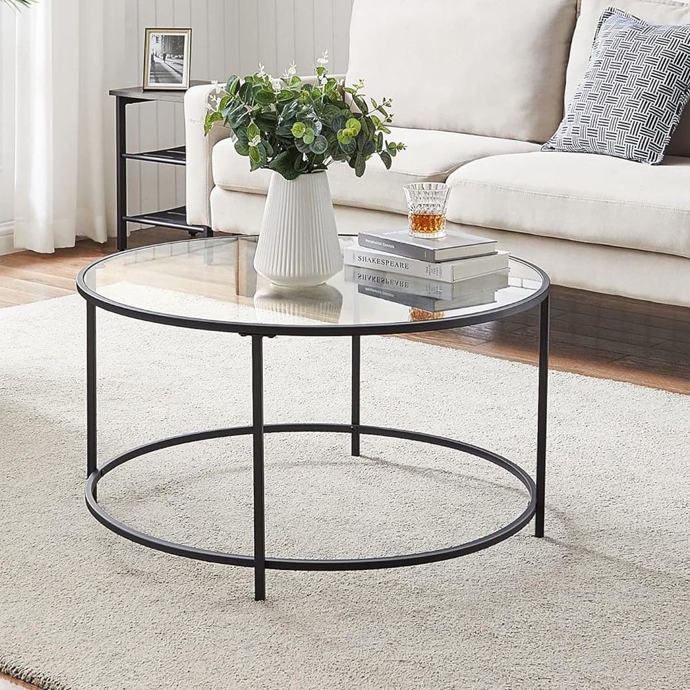 Pyöreä sohvapöytä lasitasolla ja mustalla teräsrungolla